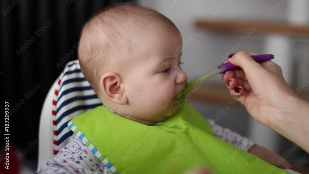 mother feeding six months old baby with spoon.close up mother feeding six months old baby with spoon.close up