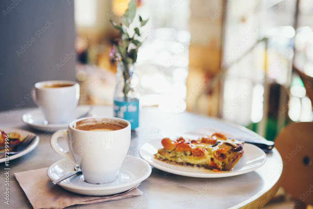 Close-up of a breakfast for two persons in a nice cafe, warm quiche and coffee, no people blurry background. Film effect. Close-up of a breakfast for two persons in a nice cafe, warm quiche and coffee, no people blurry background. Film effect.
