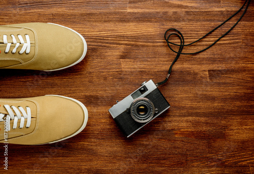 Vintage camera with sneakers on wooden background. Travel background. Horizontal