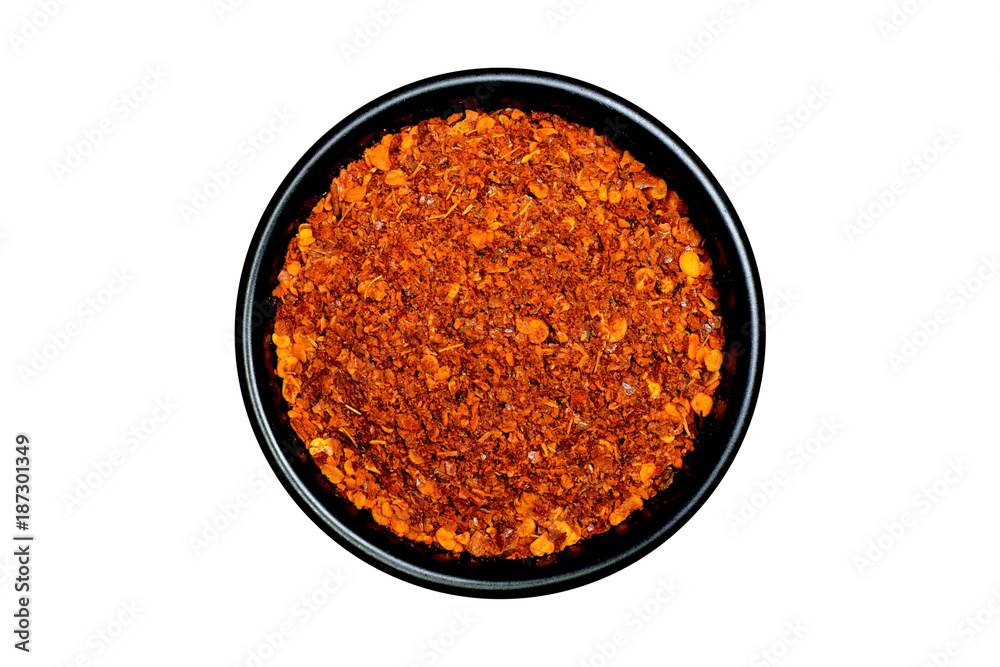 Hot red chili peppers powder in a black bowl isolated on white background