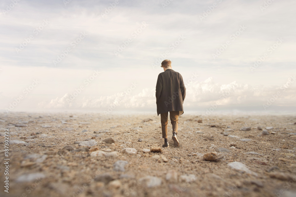 lonely man walks towards an unknown destination in a desert landscape lonely man walks towards an unknown destination in a desert landscape