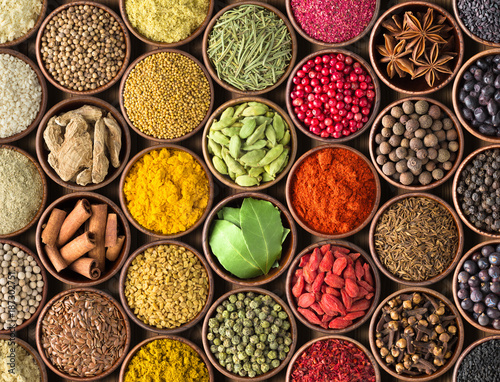 Spices and herbs background. Condiments on the table spread out by a rainbow