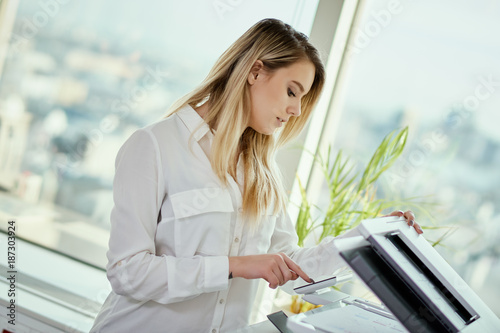 beautiful young businesswoman poses in a sunny skyscraper office photo