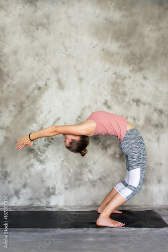 Girl doing yoga poses on the grey background © Alina