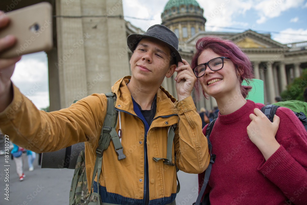 Fototapeta premium Young couple of tourists taking selfies against the Kazan cathedral in Saint-Petersburg, Russia