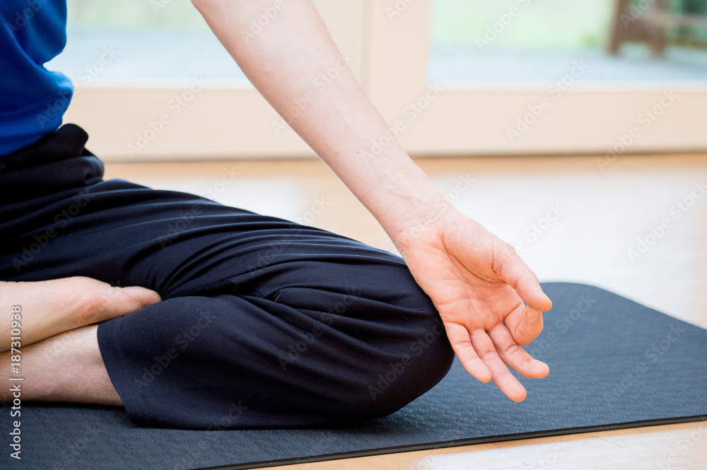 Man practicing yoga indoors in a retreat space doing a meditation in Lotus Pose - Padmāsana