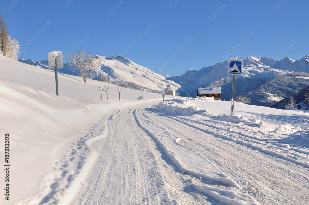 road in a mountain covered with snow in winter under blue sky road in a mountain covered with snow in winter under blue sky