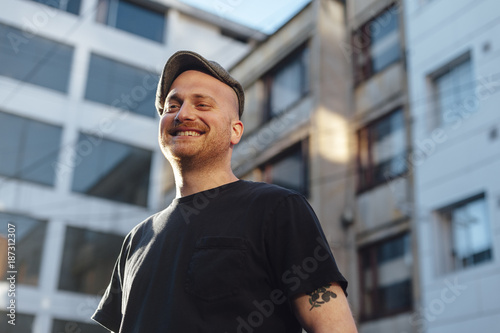 Low angle view of mid agen man wearing a cap and smiling in urban area at sunset