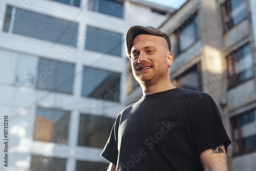 Low angle view of mid agen man wearing a cap and smiling in urban area at sunset photo