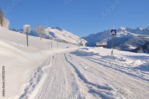 road in a mountain covered with snow in winter under blue sky © coco