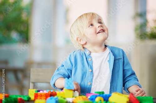 Little boy playing with colorful plastic construction blocks