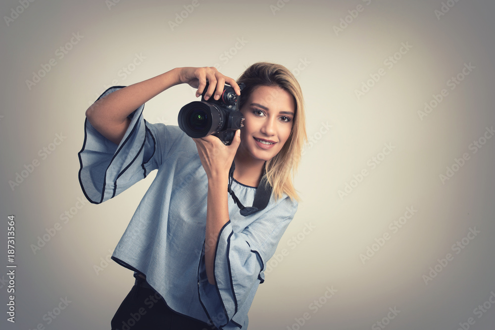 Cheerful young woman making photo on camera over gray background Cheerful young woman making photo on camera over gray background