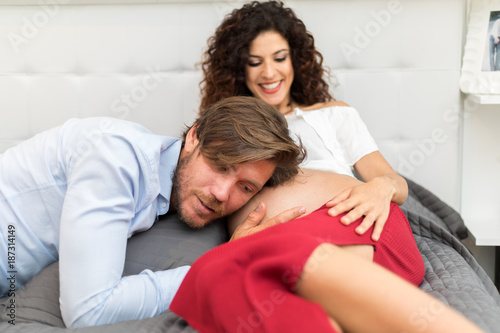 Husband listening to his baby in mom's belly