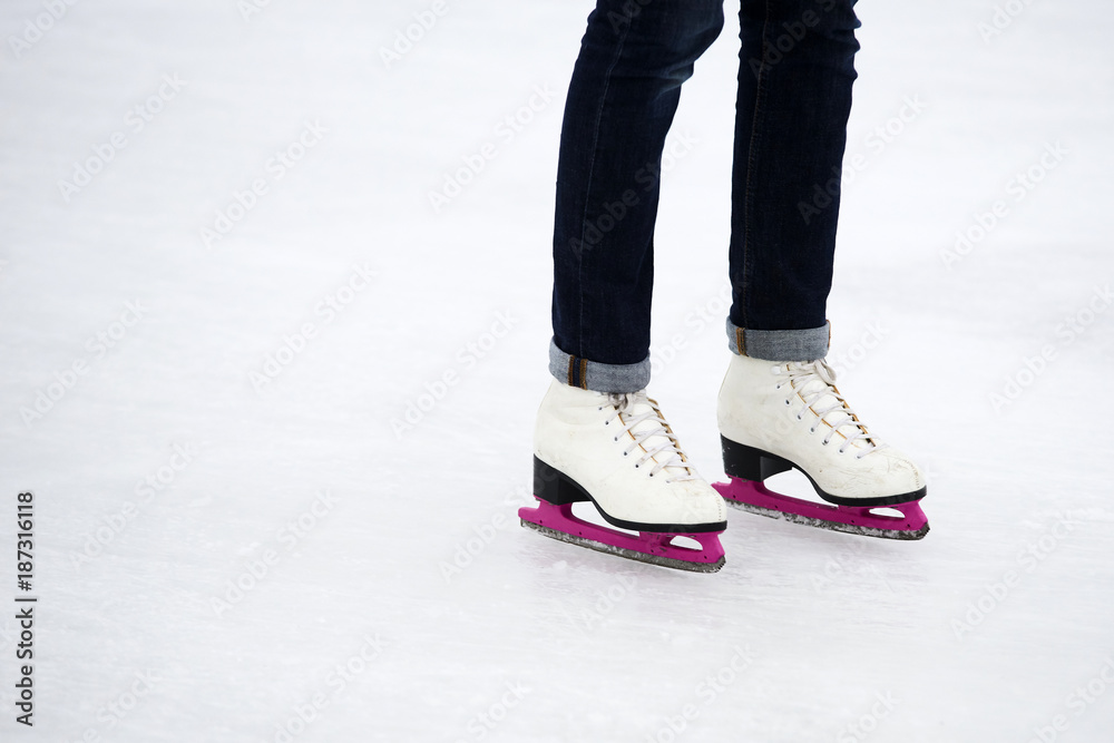 Young woman ice skating outdoors on a ice rink on a freezing winter day - detail of the legs Young woman ice skating outdoors on a ice rink on a freezing winter day - detail of the legs
