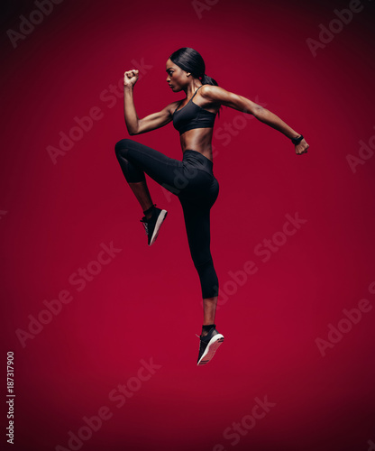 African female athlete jumping and stretching