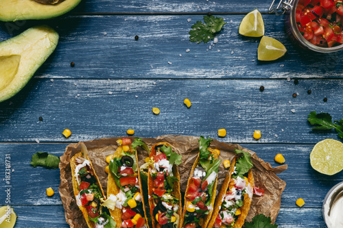 Mexican tacos with salsa and avocado on the wooden blue background, top view