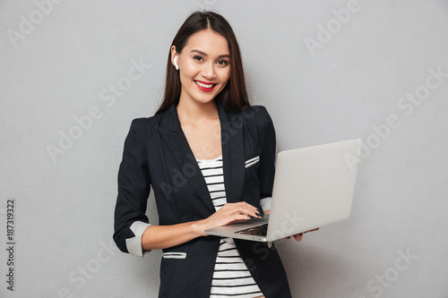 Happy business woman holding laptop computer and looking at camera