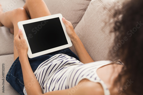 Unrecognizable girl with tablet sitting on couch