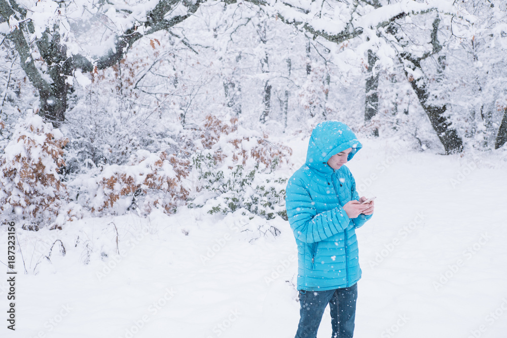 teenager with smartphone and blue jacket, snow day teenager with smartphone and blue jacket, snow day