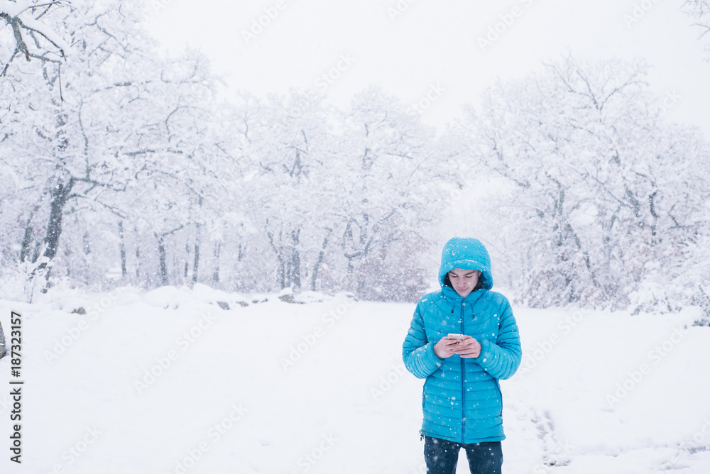 teenager with smartphone and blue jacket, snow day
