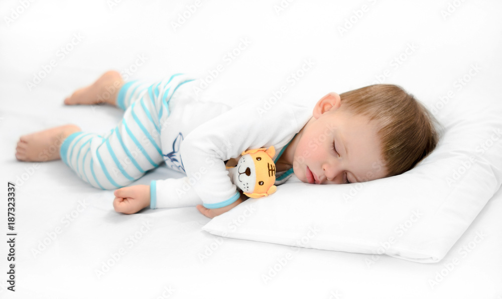Sleeping baby on white background. Toddler boy in pijama sleeps on white pillow under blanket
