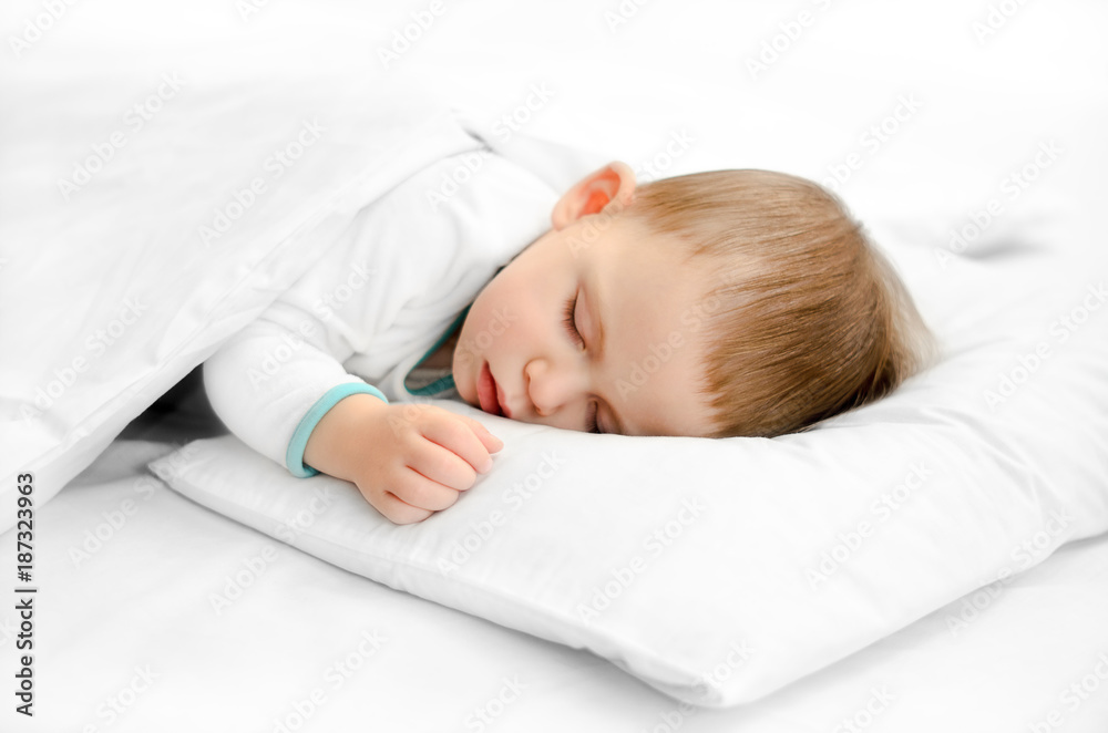 Sleeping baby on white background. Toddler boy in pijama sleeps on white pillow