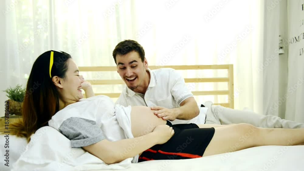 Pregnant woman in bed. Chinese pregnant woman laying in bed relaxing with her white husband. Having fun together. Pregnant woman in bed. Chinese pregnant woman laying in bed relaxing with her white husband. Having fun together.