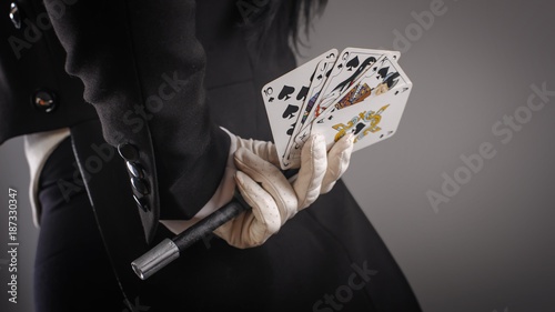 Magic wand and cards in hands of female magician. Closeup