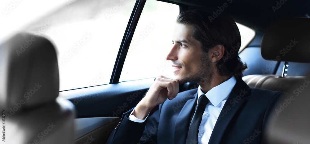 successful man sitting in the back seat of a car