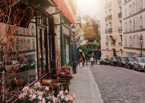 Obraz Przytulna ulica ze stolikami kawiarni i starym młynem w dzielnicy Montmartre w Paryżu, Francja