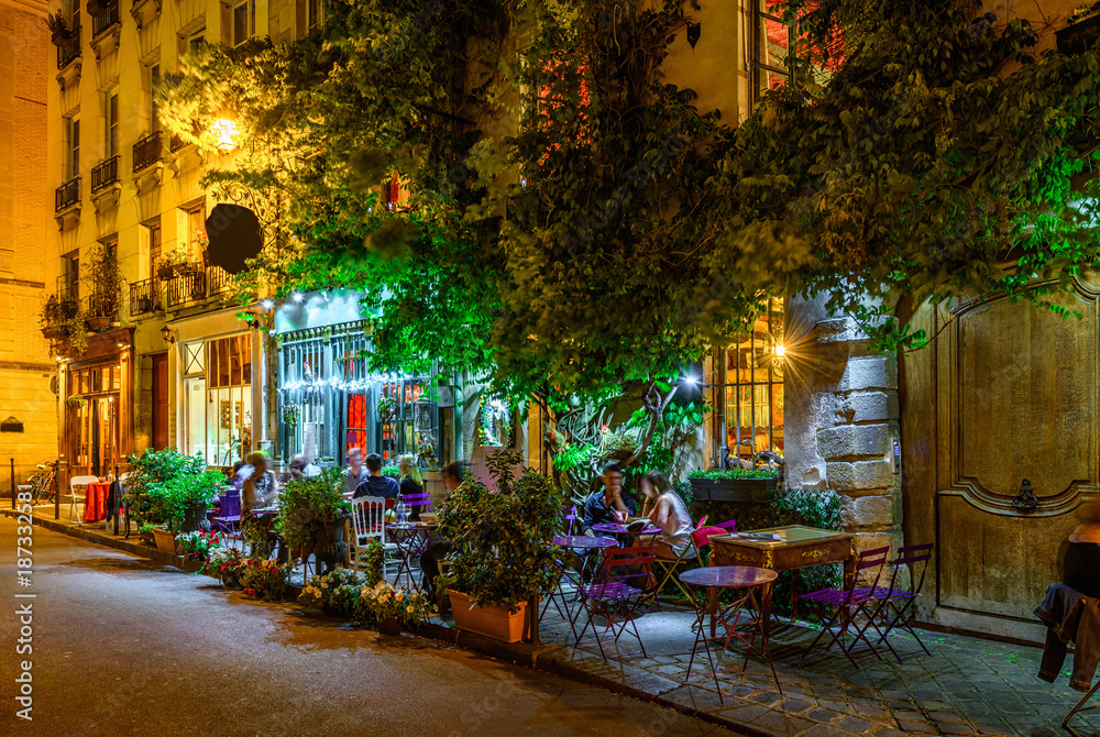 Fototapeta premium Przytulna ulica ze stołami kawiarni w Paryżu w nocy, Francja