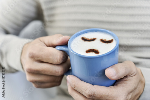 man with a cup of cappuccino with a sad face photo