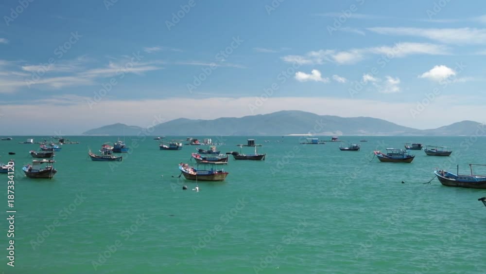 Vietnamese coastline looking out over the south china sea in Nha Trang Vietnam with a cloudy blue sky and fishing boats high definition movie footage. Vietnamese coastline looking out over the south china sea in Nha Trang Vietnam with a cloudy blue sky and fishing boats high definition movie footage.