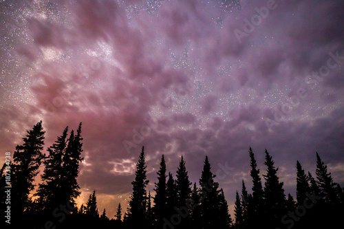 Cloudy night time landscape with stars. Spotted clouds cover most of the sky with the milkyway way slightly visible behind.