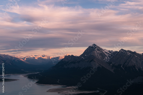 Snowy Swirls in mountain at sunset. The mountain shows a unique pattern in the mountainside with snow and Abraham lake at its base. The last of the sun shines of mountains in the distance.
