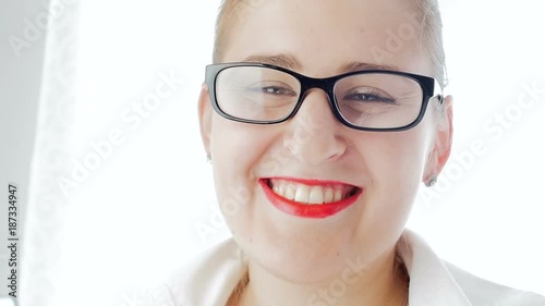 Closeup slow motion video of beautisul smiling woman wearing eyeglasses looking in camera photo