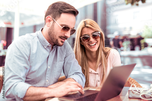 Young man and woman working on laptop in cafe.