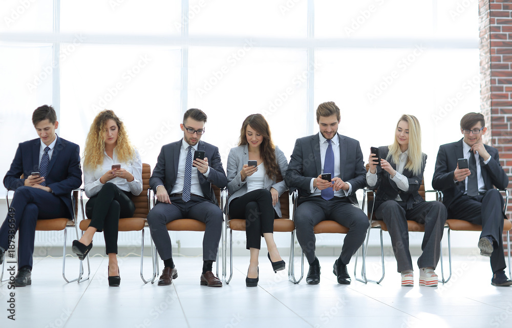 employees with smartphones sitting in the lobby employees with smartphones sitting in the lobby