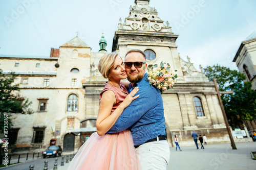 Happy romantic couple whirling on european city square. The groom hugging bride and they are looking at camera. © Iryna