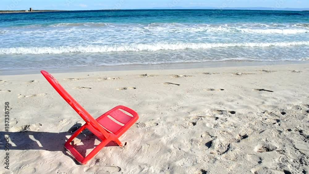 red plastic chair in an empty beach in Sardinia red plastic chair in an empty beach in Sardinia