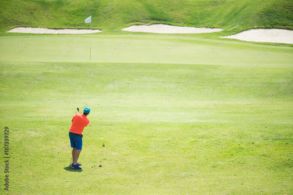 Obraz premium Golfer hitting golf shot with club on course while on summer vacation,Man playing golf on a golf course in the sun
