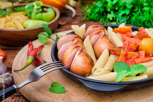 Pasta with sausages and lecho. Wooden rustic background. Selective focus. Top view photo