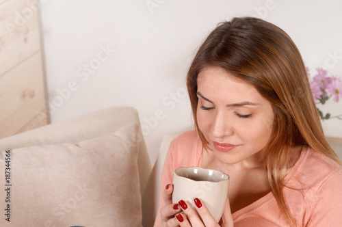 Young woman sitting on the sofa and drinking tea or coffee