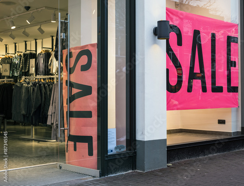 the word sale in shop window of clothing store with open door