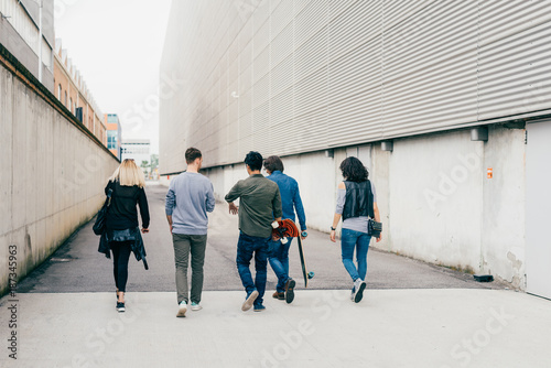 Slika na platnu back view group of friends multiethnic walking outdoor having fun - friendship,