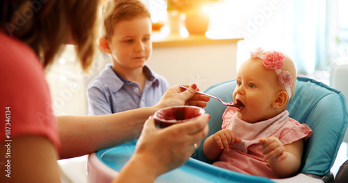 Pleasant young woman feeding a cute baby