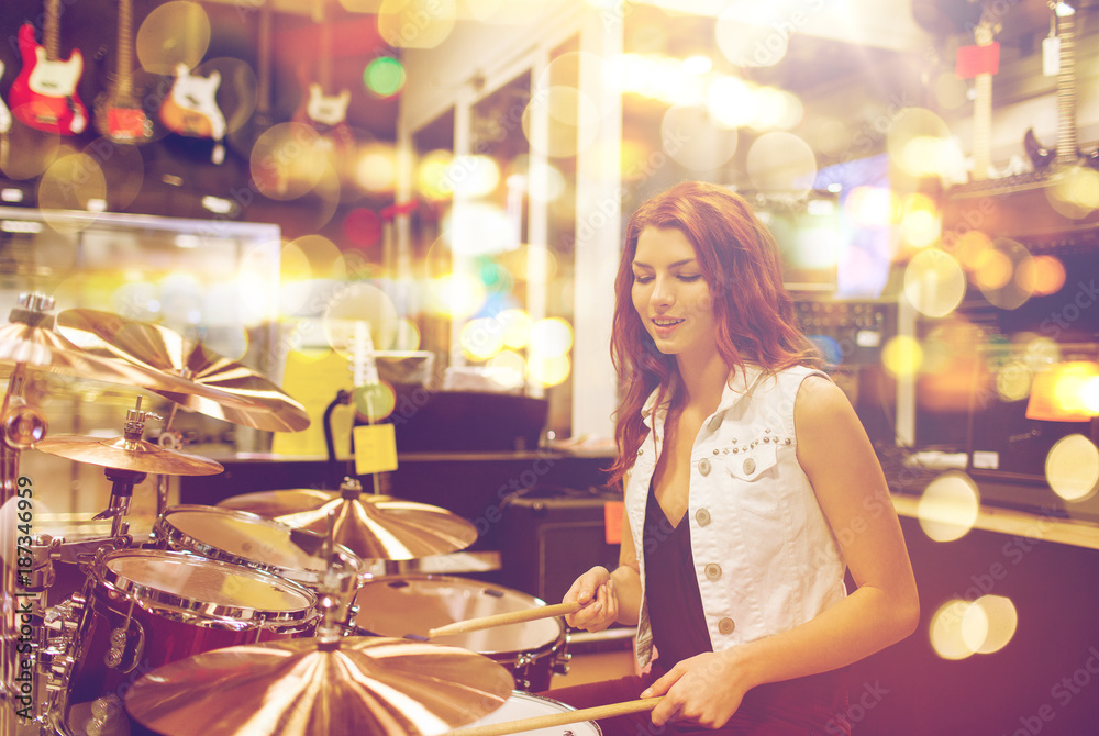 female musician playing drum kit at music store