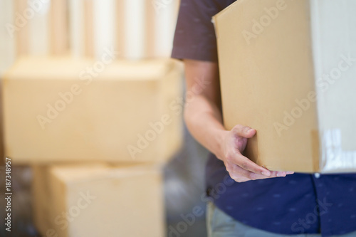 close up man hand carrying big box for moving from old home to new home , relocation concept
