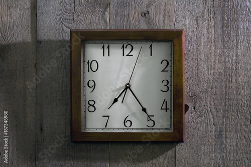 the clock hangs on a wooden wall
