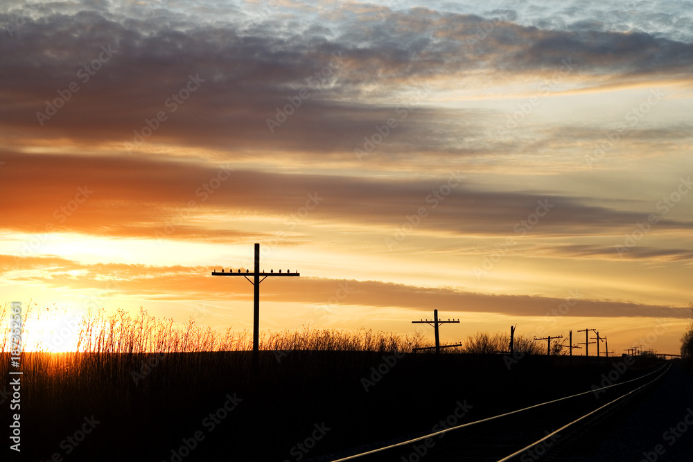 Railway next to the old telephone poles at sunset